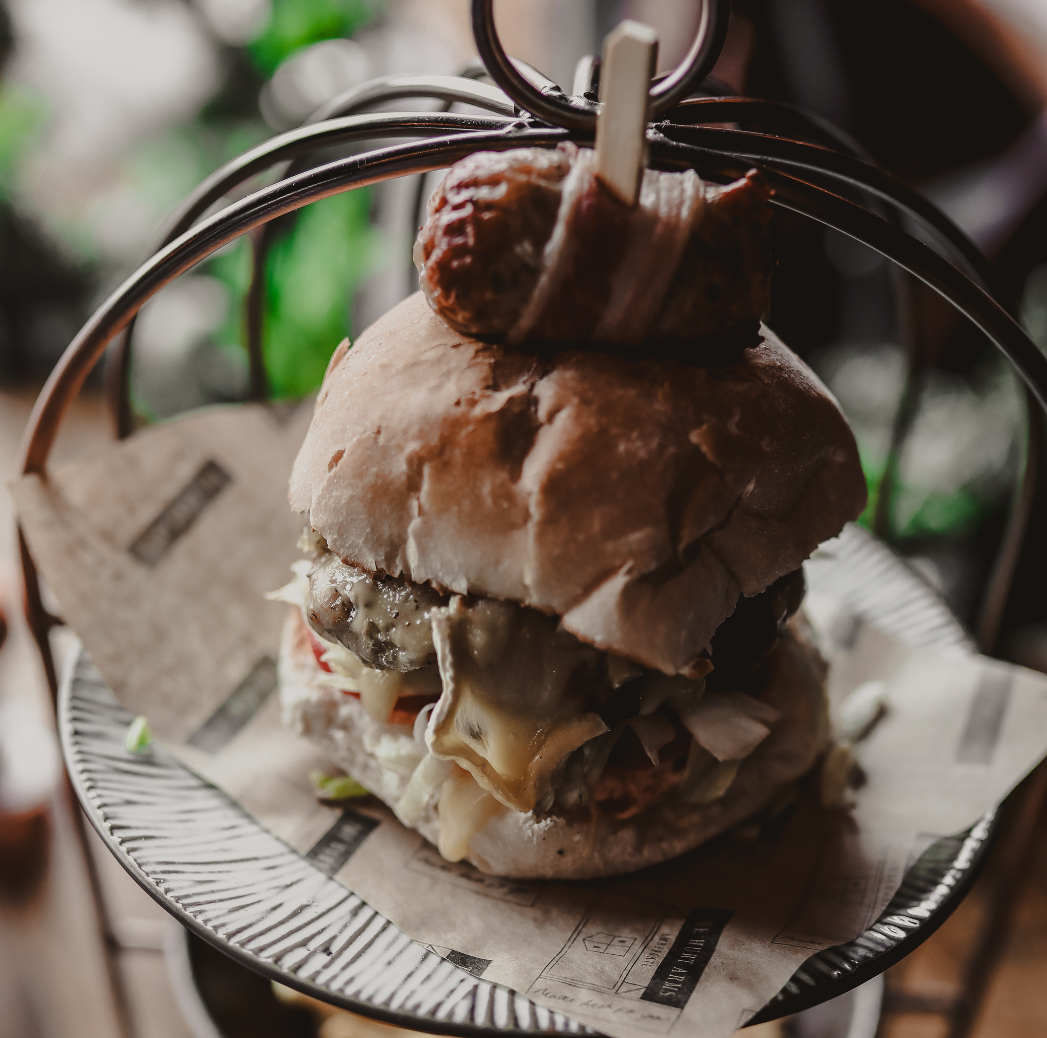 burger on a metal cage stand with a pigs in blanket on the top