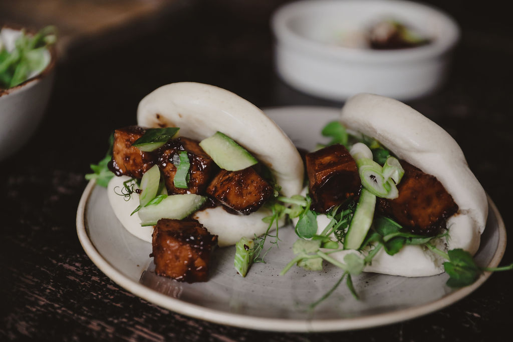 two bao buns with tofu and relish on a white plate