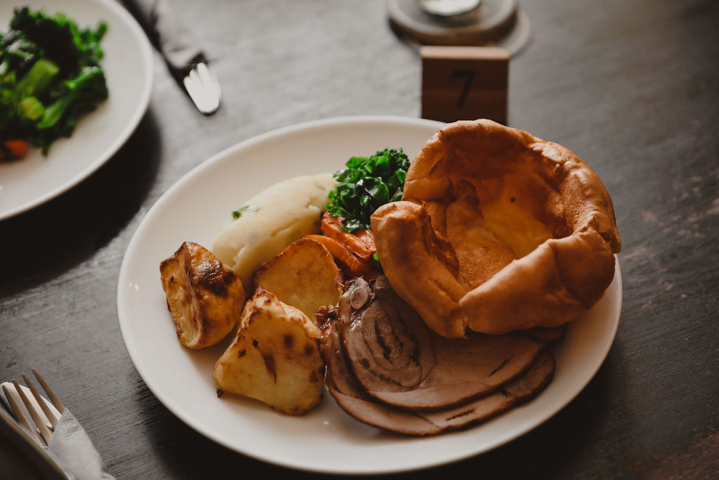 a roast dinner on a white plate with a giant Yorkshire Pudding