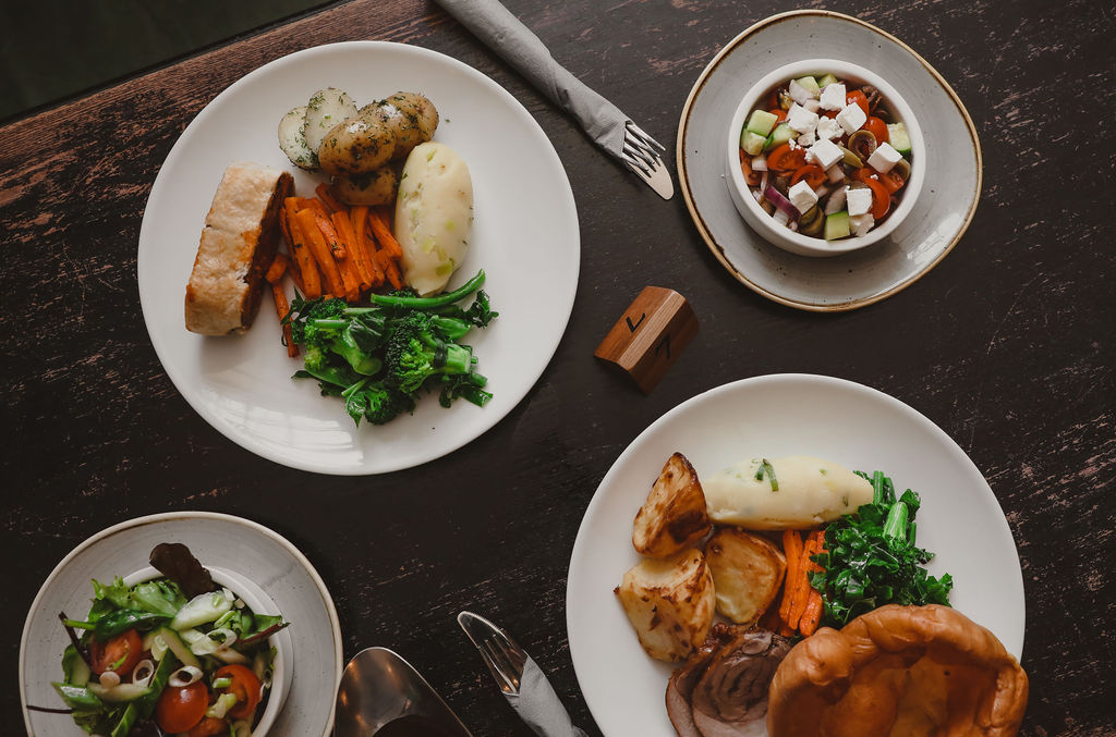 four plates of food on a wooden table taken from above