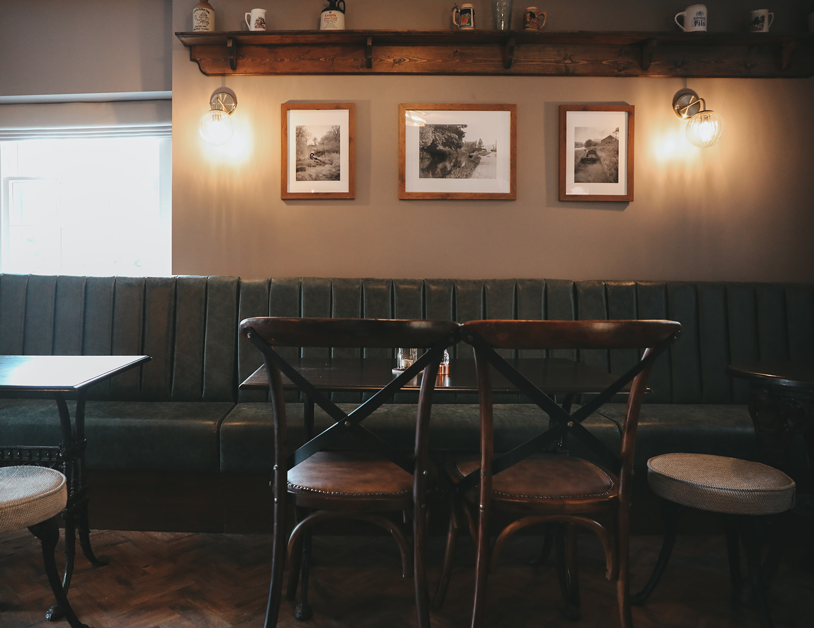 green fixed seating in pub room with chairs and wall lights