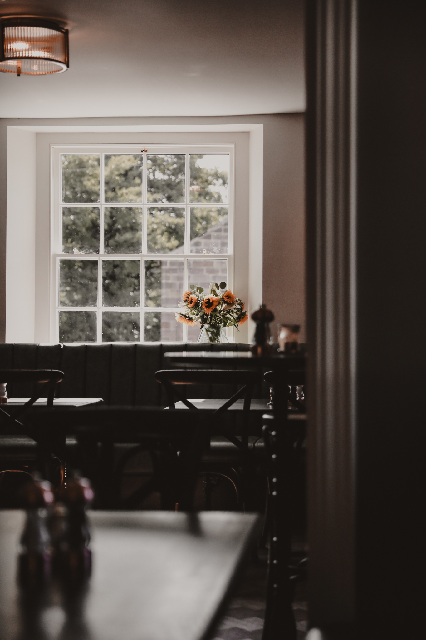 large window with tables in front and daffodils in the window