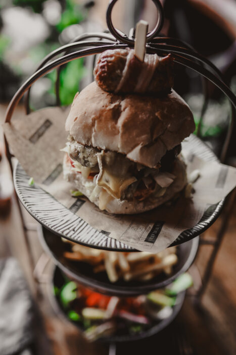 burger on a metal cage stand with a pigs in blanket on the top