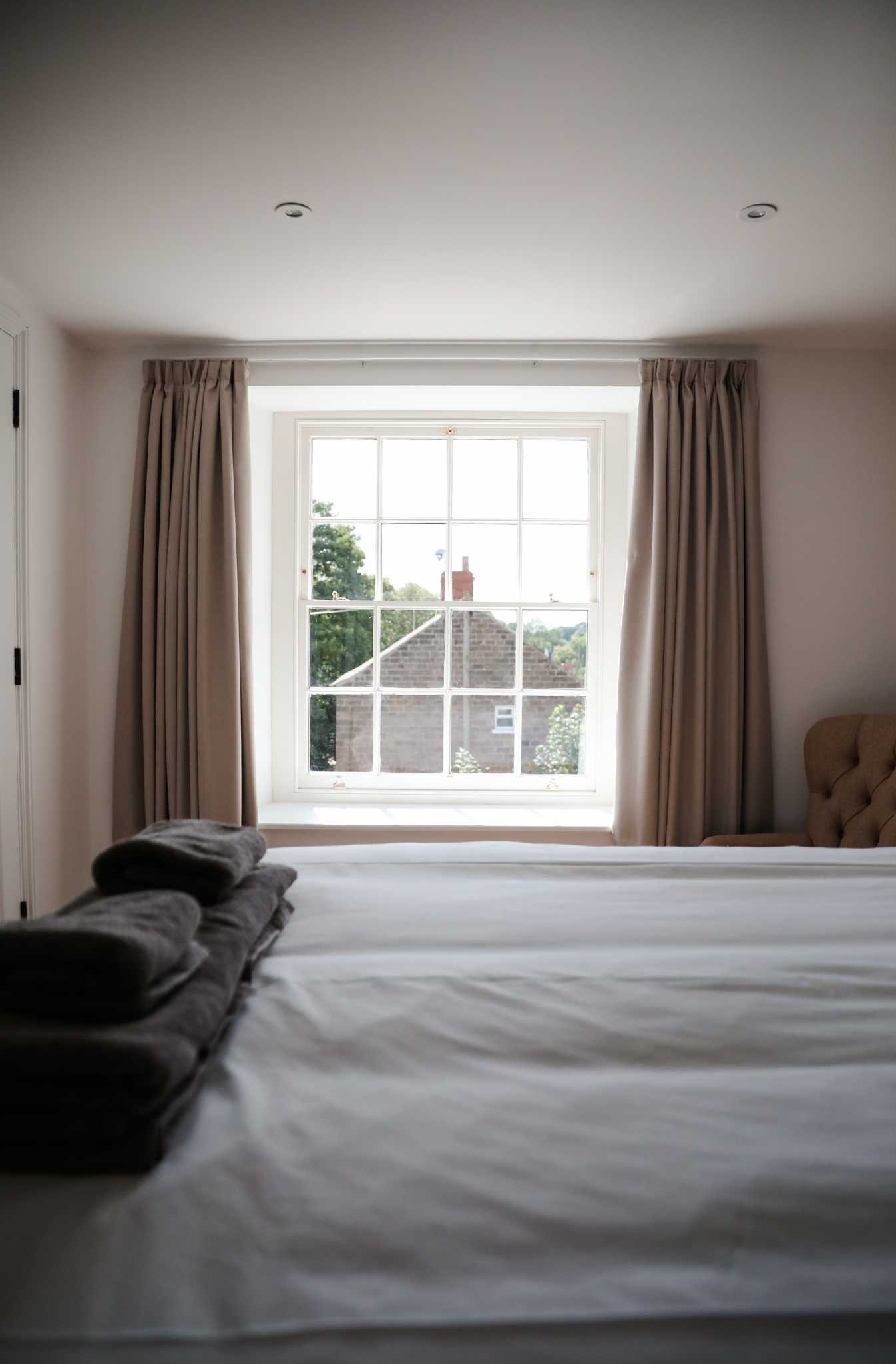large window with curtains and a bed in front