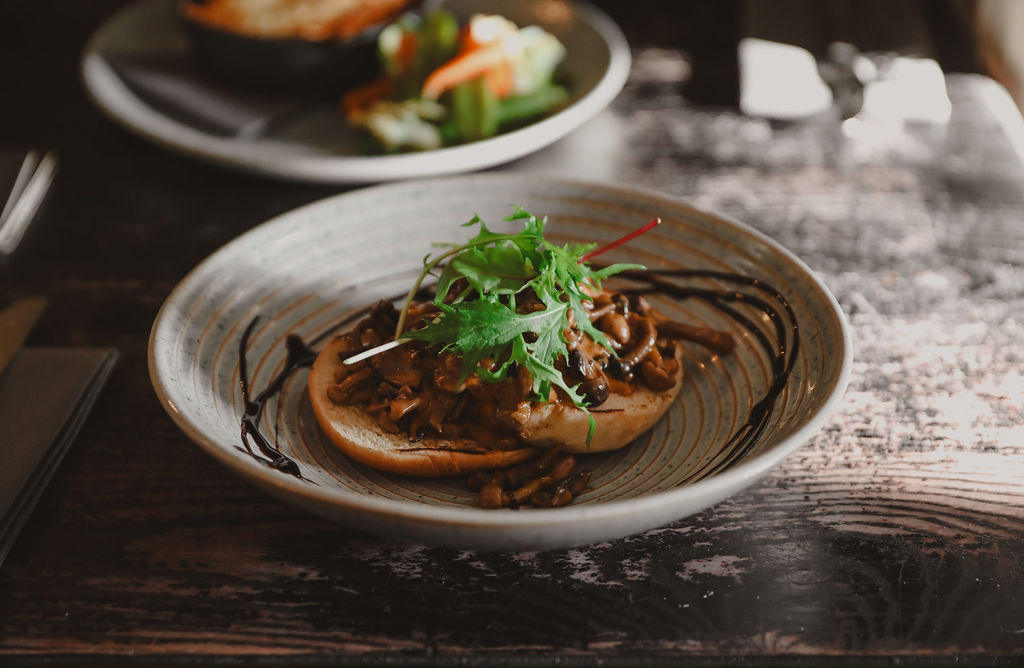 a bowl with toast and creamy mushrooms with a drizzle around the edge