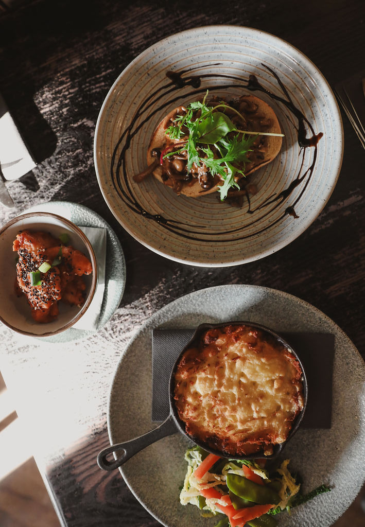 three plates on a table with a pie dish and green garnishes