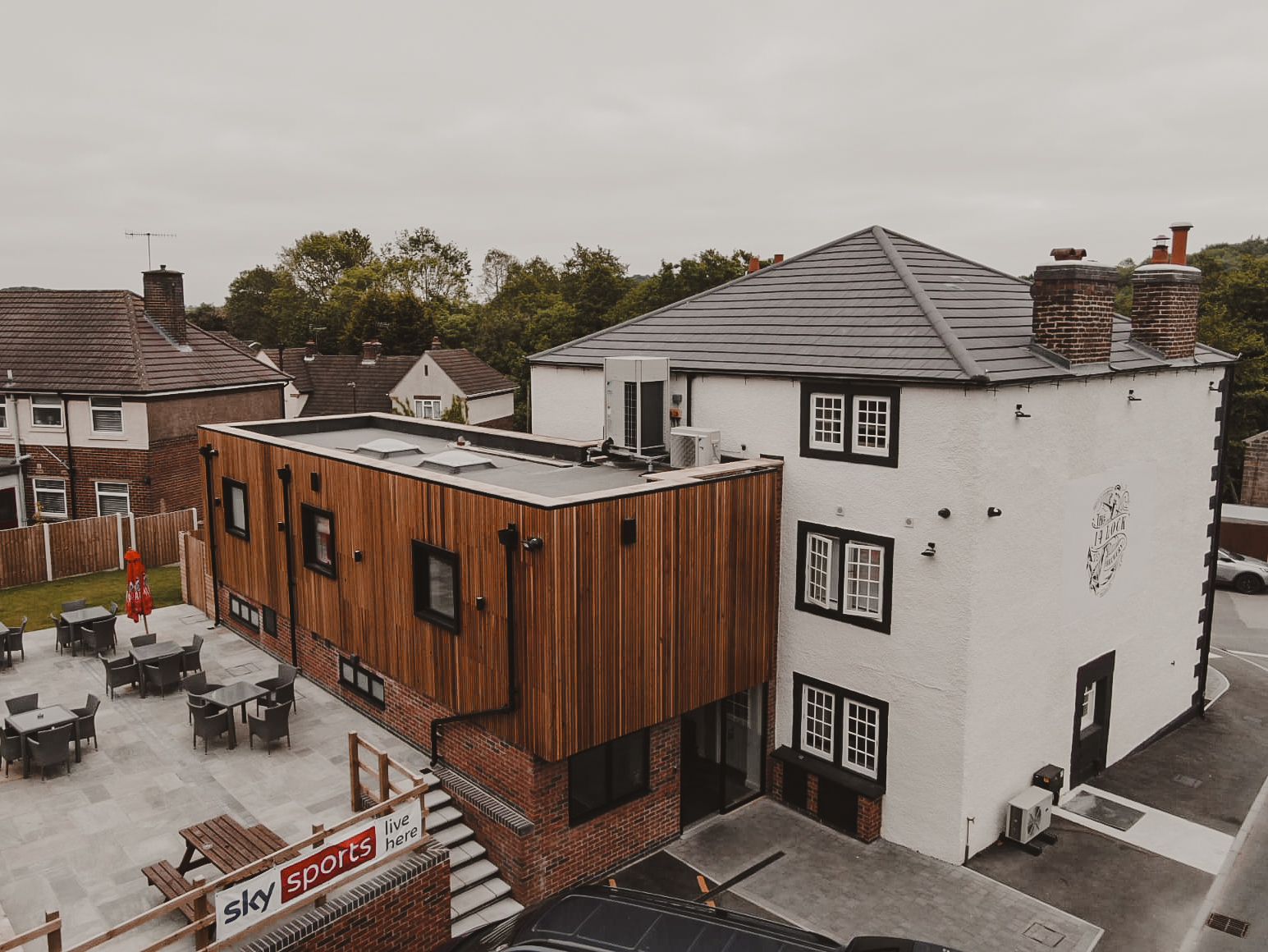 big white building with wooden extension off the back and wooden benches